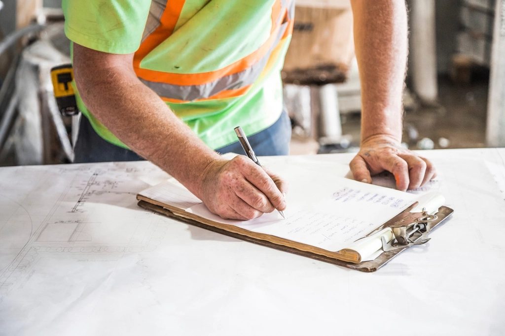 Project lead reviewing plans on a clipboard at a job site